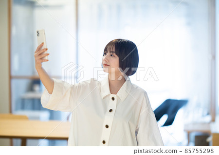 一個女人在室內拿著智能手機 一個女人在室內拿著智能手機 85755298
