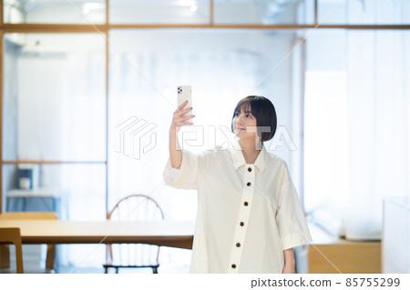 一個女人在室內拿著智能手機 一個女人在室內拿著智能手機 85755299