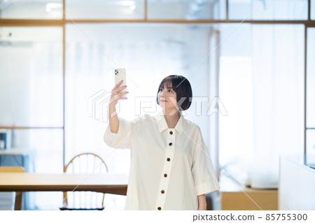 一個女人在室內拿著智能手機 一個女人在室內拿著智能手機 85755300