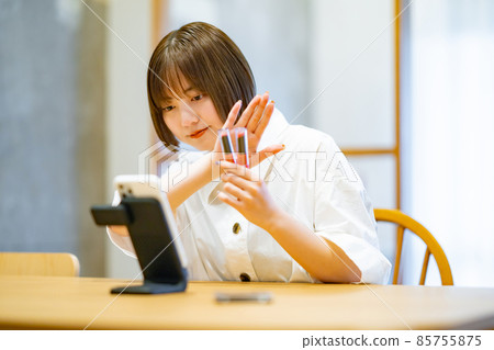 A woman using a smartphone to introduce cosmetic goods 85755875