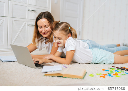 Happy family learning from home together lying on floor in children room looking on laptop screen. Happy family learning from home together lying on floor in children room looking on laptop screen. 85757088