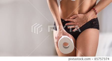 Digestive problems as woman holds her belly with one hand, holding a toilet paper in the other hand Digestive problems as woman holds her belly with one hand, holding a toilet paper in the other hand 85757374