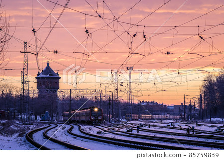 The passenger train travels on the tracks on a cold winter morning in the city. Selective focus 85759839