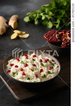 Curd Rice with pomegranate, cilantro, mustard seeds, ginger on a black background. Indian cuisine 85760130