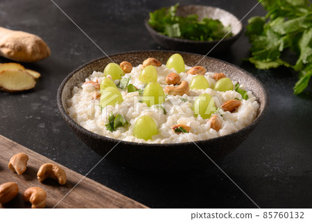 Curd Rice with cashews, grapes, cilantro, ginger on a black background. Indian cuisine 85760132
