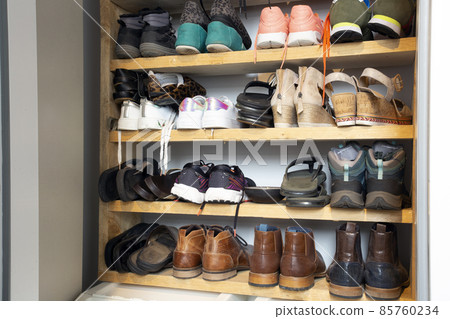 Collection of different shoes in shoe rack for storage, messy and needs organize, wardrobe with shelfs in house interior design stylish decoration 85760234