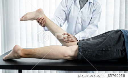 Female physiotherapist doing healing treatment and rehabilitation injured legs and ankle of patient by stretching 85760956