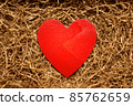 Present box with big red heart lying on brown shredded craft paper filler 85762659