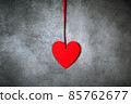 Minimalistic decoration, red heart over textured grey background 85762677