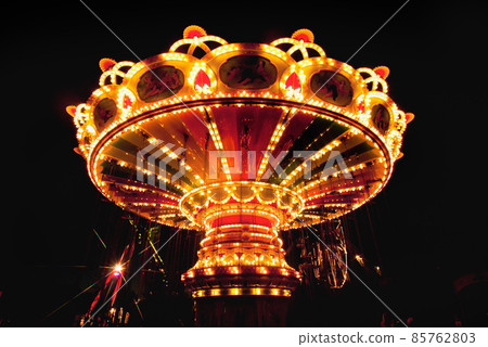 Colorful chain swing carousel in motion at amusement park at night. 85762803