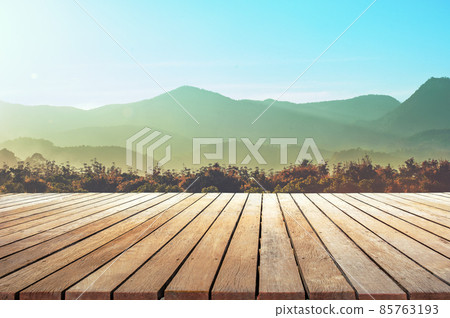 empty wooden table top with the mountain landscape against sunset sky 85763193