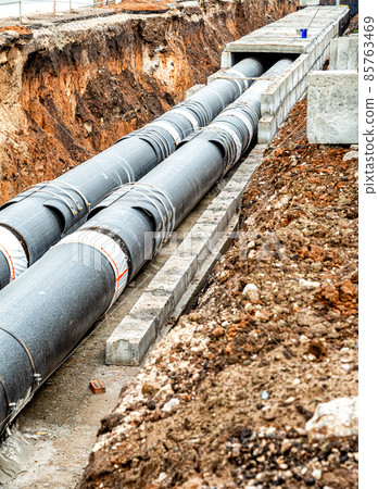 Construction works on large iron pipes at a depth of excavated trench 85763469