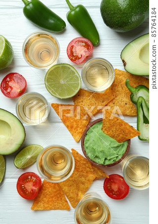 Party concept with tequila, guacamole and chips Party concept with tequila, guacamole and chips 85764184