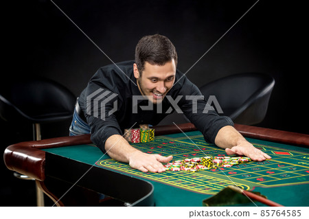Young handsome man playing roulette wins at the casino 85764585
