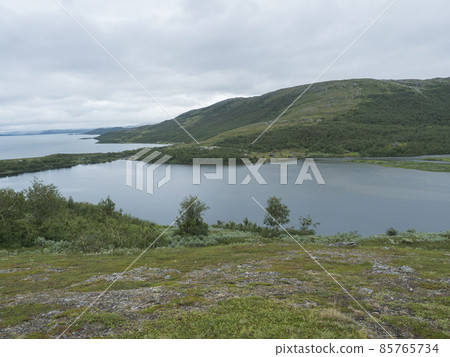 Lapland landscape at Virihaure lake with sami village Staloluokta houses and cottage, snow capped mountains and birch trees. Sweden summer moody and foggy wild nature, Padjelantaleden hiking trail. Lapland landscape at Virihaure lake with sami village Staloluokta houses and cottage, snow capped mountains and birch trees. Sweden summer moody and foggy wild nature, Padjelantaleden hiking trail. 85765734