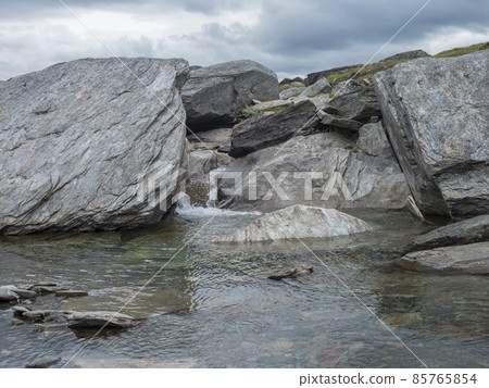 Water runs over the top of big grey stone boulders at water stream at arctic northern landscape in Swedish Lapland Water runs over the top of big grey stone boulders at water stream at arctic northern landscape in Swedish Lapland 85765854