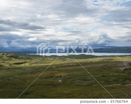 Lapland landscape at Virihaure lake with winding river, green mountains, birch trees and plain with big boulders. Sweden summer cloudy day, wild nature, Padjelantaleden hiking trail. 85766764
