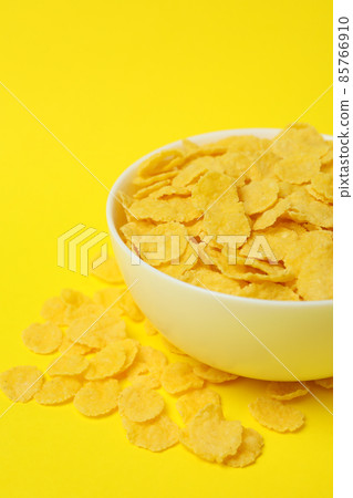 Bowl of corn flakes on yellow background Bowl of corn flakes on yellow background 85766910