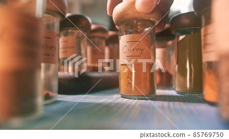Putting bottle with curry on the table among other spices Putting bottle with curry on the table among other spices 85769750