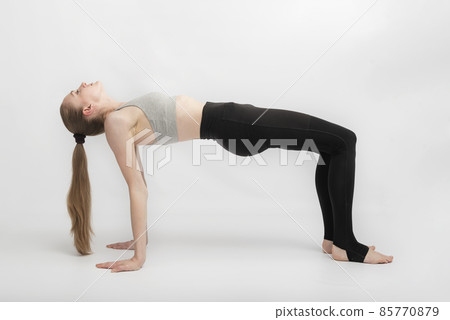 Young slender woman practices yoga on white background. Beautiful athletic body. Ardha Purvottanasana. Reverse Table Pose. 85770879