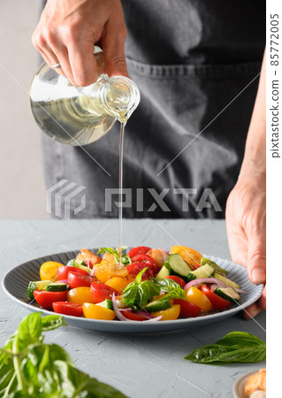 Woman cooking Panzanella salad from fresh vegetables. 85772005