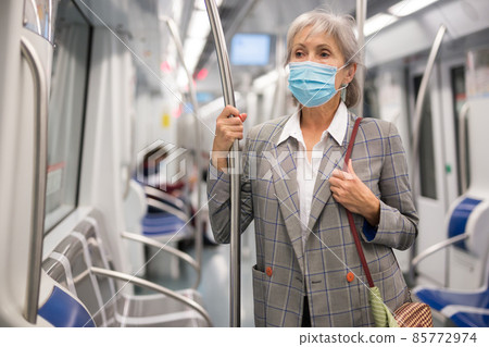 Senior lady in mask standing in metro train Senior lady in mask standing in metro train 85772974