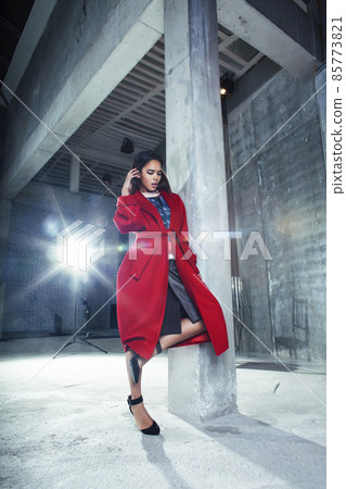young pretty african american woman in luxury red coat posing fashionable on empty parking building, lifestyle rich people concept 85773821