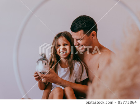 Happy affectionate loving single father and cute small child daughter bonding embracing laughing sit on sofa. Happy affectionate loving single father and cute small child daughter bonding embracing laughing sit on sofa. 85773864