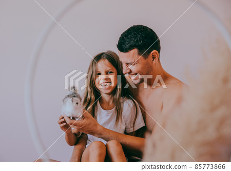 Happy affectionate loving single father and cute small child daughter bonding embracing laughing sit on sofa. Happy affectionate loving single father and cute small child daughter bonding embracing laughing sit on sofa. 85773866