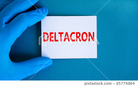 Covid-19 corona deltacron variant symbol. Hand in blue glove with white card. The concept word Deltacron. Medical and COVID-19 corona deltacron variant concept. Copy space. Covid-19 corona deltacron variant symbol. Hand in blue glove with white card. The concept word Deltacron. Medical and COVID-19 corona deltacron variant concept. Copy space. 85774864