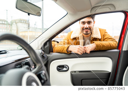 Man casually dressed with hands holding driving wheel riding car at daytime Man casually dressed with hands holding driving wheel riding car at daytime 85775043