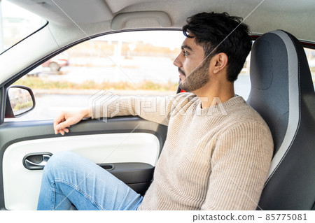Man in sweater sitting on passenger's seat having ride in car at daytime Man in sweater sitting on passenger's seat having ride in car at daytime 85775081