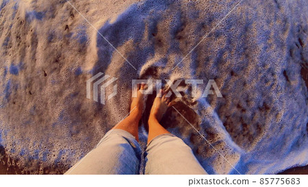Girl standing on sandy beach. Sea ocean wave with white foam rolls Girl standing on sandy beach. Sea ocean wave with white foam rolls 85775683