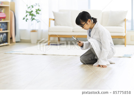 A girl in a white coat looking into a magnifying glass in the living room A girl in a white coat looking into a magnifying glass in the living room 85775858