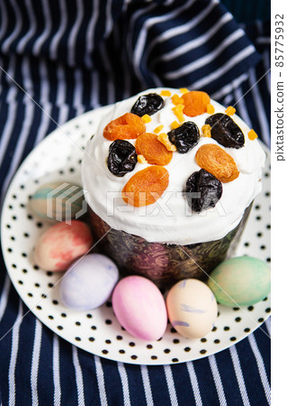Easter eggs and Easter cake lie on a plate lying on a striped blue apron. Easter religious holiday concept. Easter eggs and Easter cake lie on a plate lying on a striped blue apron. Easter religious holiday concept. 85775932
