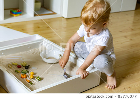 Cute toddler playing self development home kinetic sandbox use Maria Montessori method Cute toddler playing self development home kinetic sandbox use Maria Montessori method 85776077