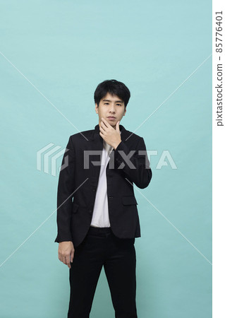 Handsome Asian man in a black suit looking at camera 85776401