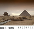 Egyptian Great Sphinx full body portrait with head, feet with all pyramids of Menkaure, Khafre, Khufu in background on a clear, blue sky day in Giza, Egypt empty with nobody. copy space 85776722