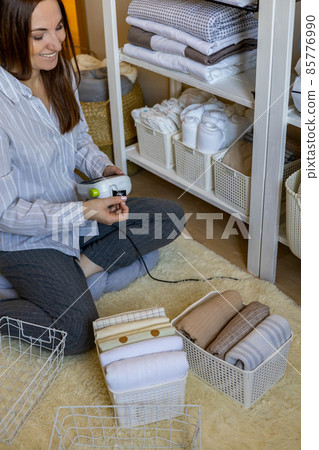 Woman neatly folded linens and towels use Marie Kondo method with sticky label tags Woman neatly folded linens and towels use Marie Kondo method with sticky label tags 85776990