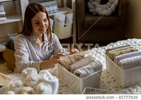 Woman neatly folded linens and towels use Marie Kondo method with sticky label tags Woman neatly folded linens and towels use Marie Kondo method with sticky label tags 85777020
