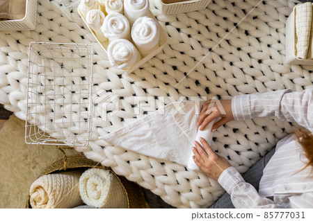 Top view female hands neatly folded white clean towels in case box use Marie Kondo organizing method Top view female hands neatly folded white clean towels in case box use Marie Kondo organizing method 85777031