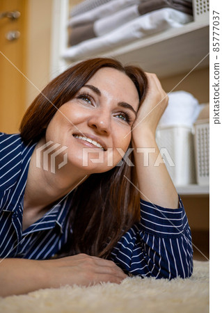 Closeup portrait happy young woman in pajamas relaxing lying on floor at bedroom general cleanup 85777037