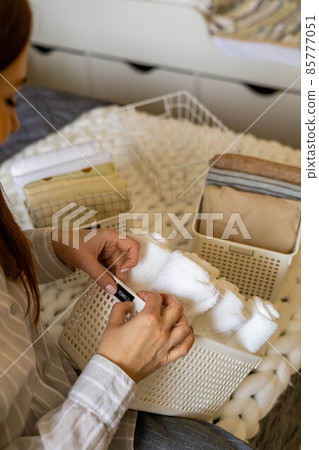 Woman hands neatly folded linens and towels use Marie Kondo method with sticky label tags Woman hands neatly folded linens and towels use Marie Kondo method with sticky label tags 85777051