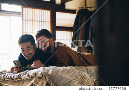 Homosexual couple LGBTQ image looking at a smartphone in bed Homosexual couple LGBTQ image looking at a smartphone in bed 85777666