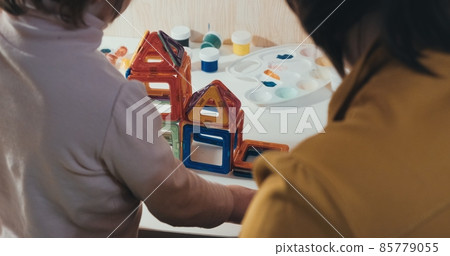 Child with his mother collects a magnetic constructor, a close up shot, a rear view, no faces are visible. The concept of development, joint family pastime and education of the child in a playful way Child with his mother collects a magnetic constructor, a close up shot, a rear view, no faces are visible. The concept of development, joint family pastime and education of the child in a playful way 85779055