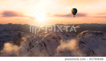 Dramatic Mountain Landscape covered in clouds and Hot Air Balloon Flying 85780686
