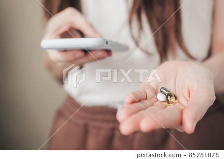 Vitamins for every day and a phone in the hands of the girl. spirulina, fish oil and magnesium in hands. Vitamins for every day and a phone in the hands of the girl. spirulina, fish oil and magnesium in hands. 85781078