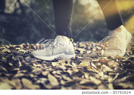 The feet of a woman walking in sneakers 85781624