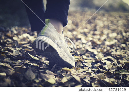 The feet of a woman walking in sneakers 85781629