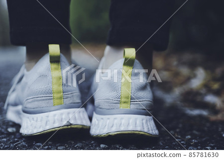The feet of a woman walking in sneakers 85781630